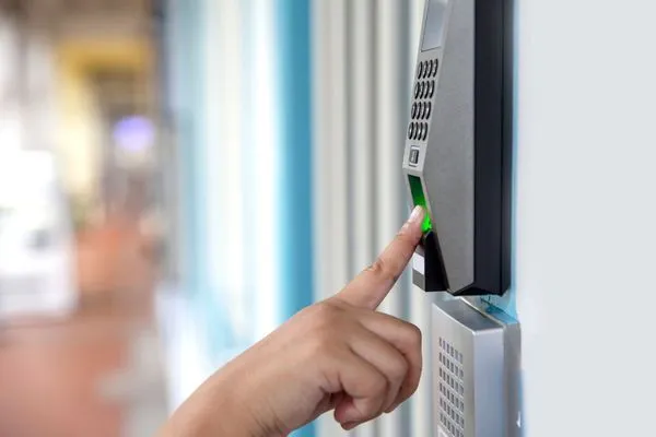 Fingerprint scanner being used to grant access to a building; person's finger on sensor, green light active.